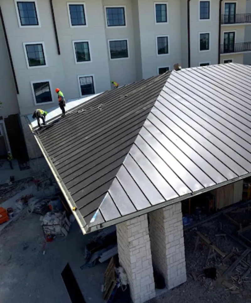 Crew installing standing seam metal roof panels on a commercial project in Albertville